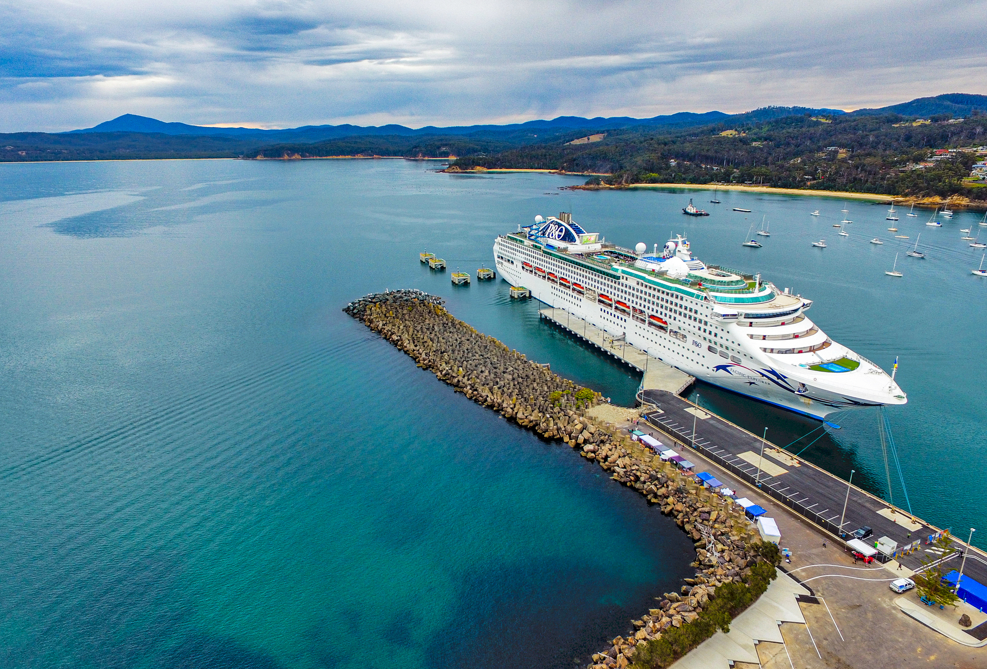 Aerial of cruise ship moored in Eden surrounded by vast expanse of water and hills