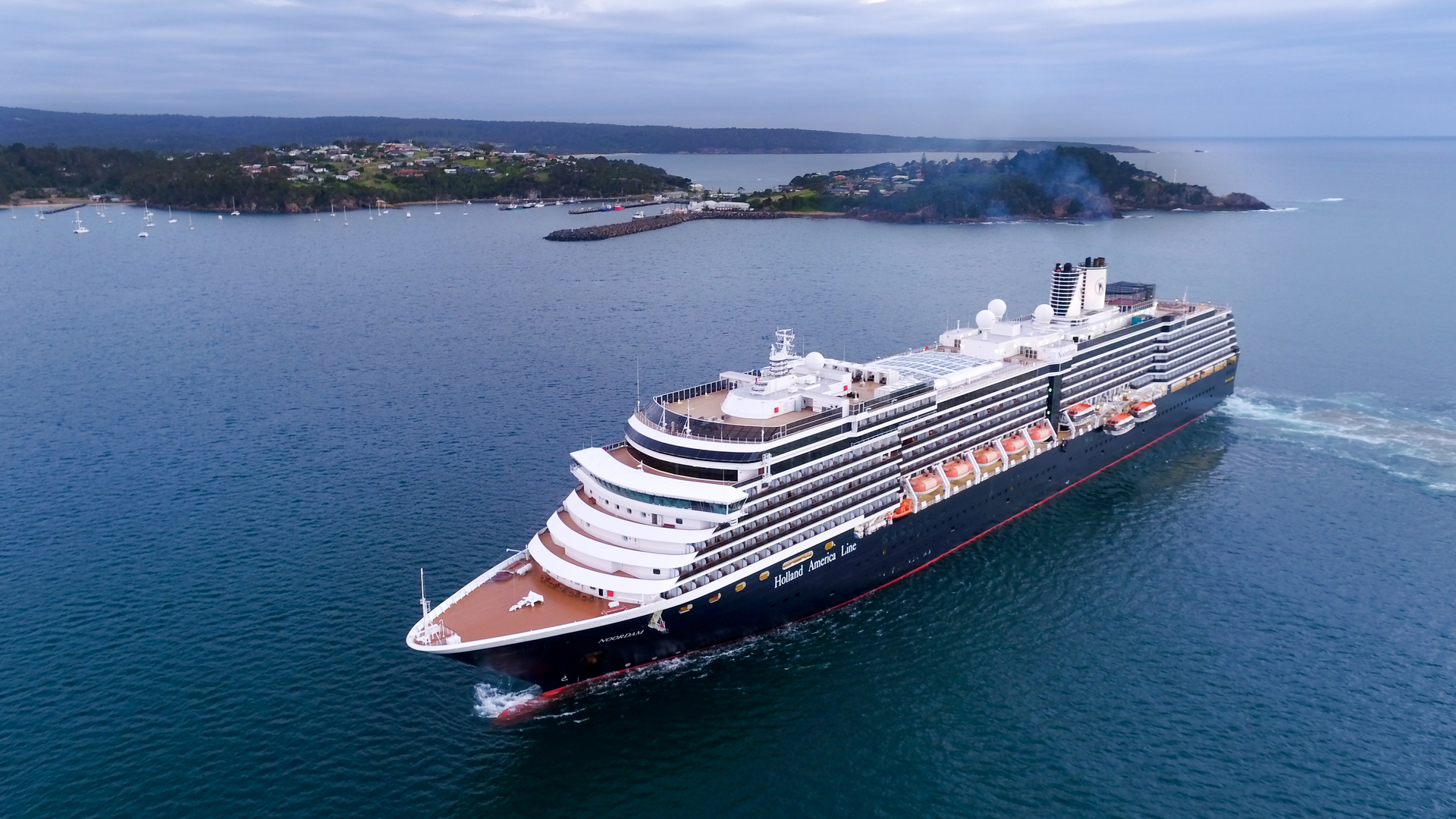 Aerial of a cruise ship off Port of Eden with Eden town in the distant background