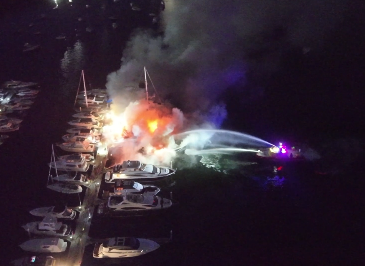 A Port Authority vessel pumps water onto several yachts on fire