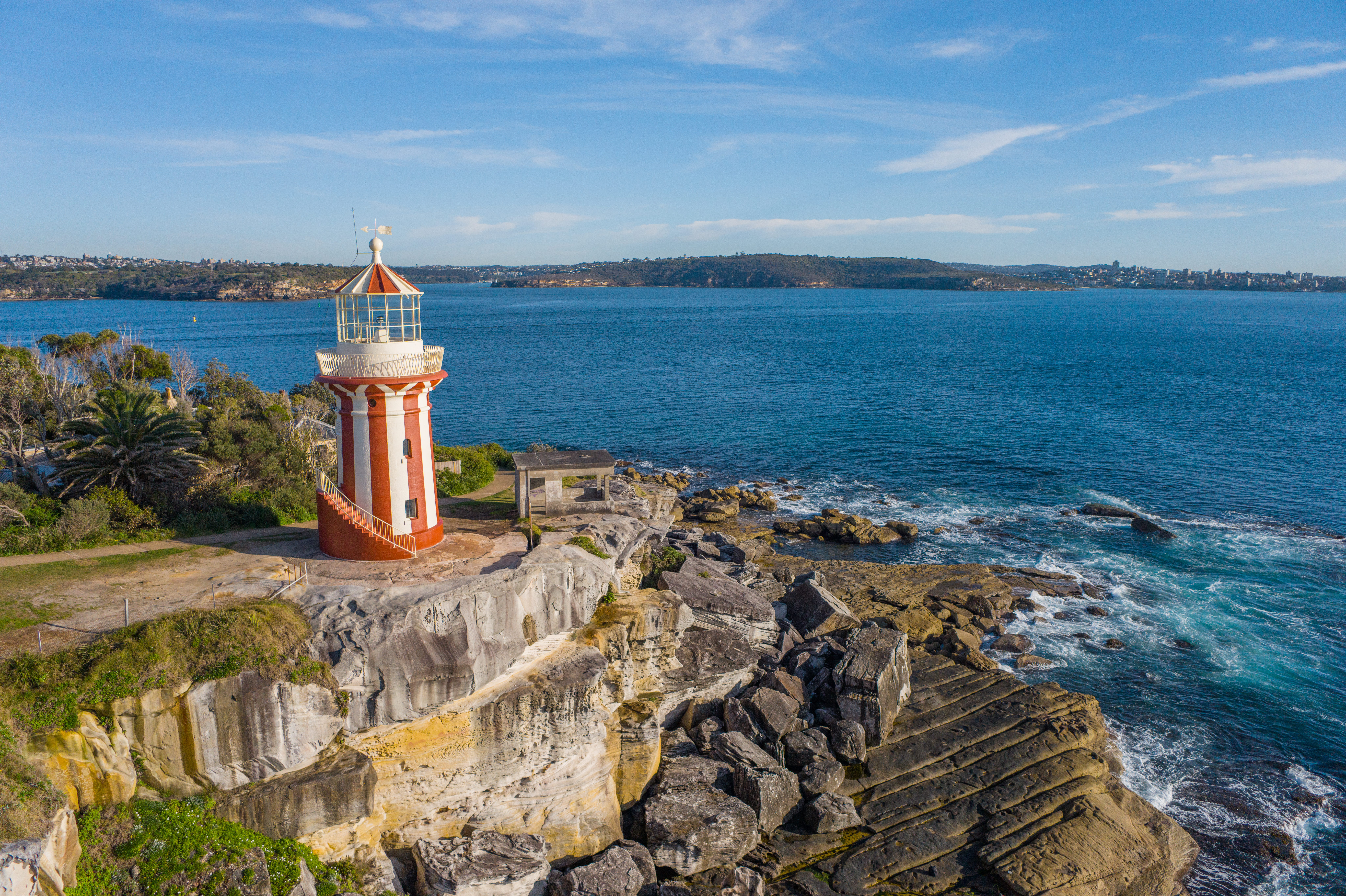 An image of a lighthouse with red and white stripes on top of a cliff