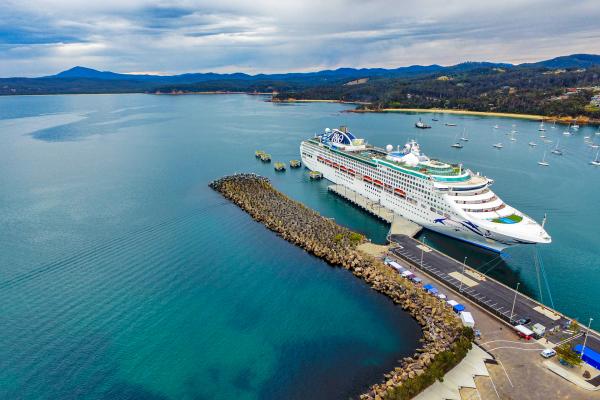 Aerial of cruise ship moored in Eden surrounded by vast expanse of water and hills
