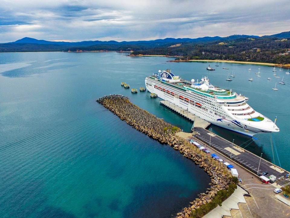 Aerial of cruise ship moored in Eden surrounded by vast expanse of water and hills
