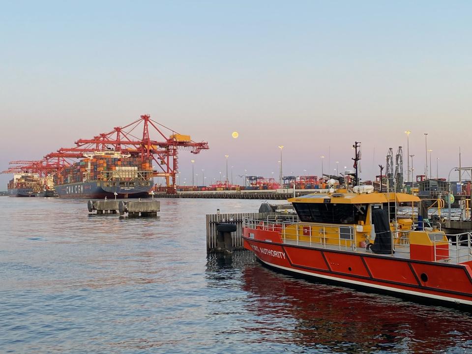 Port Authority vessel on the water at Port Botany with cranes in the distance and the moon in the sky at sunset