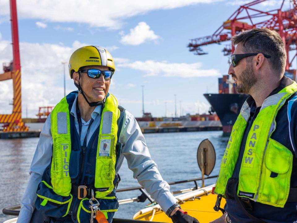 Two Port Authority workers on board a boat in high vis talking two each other