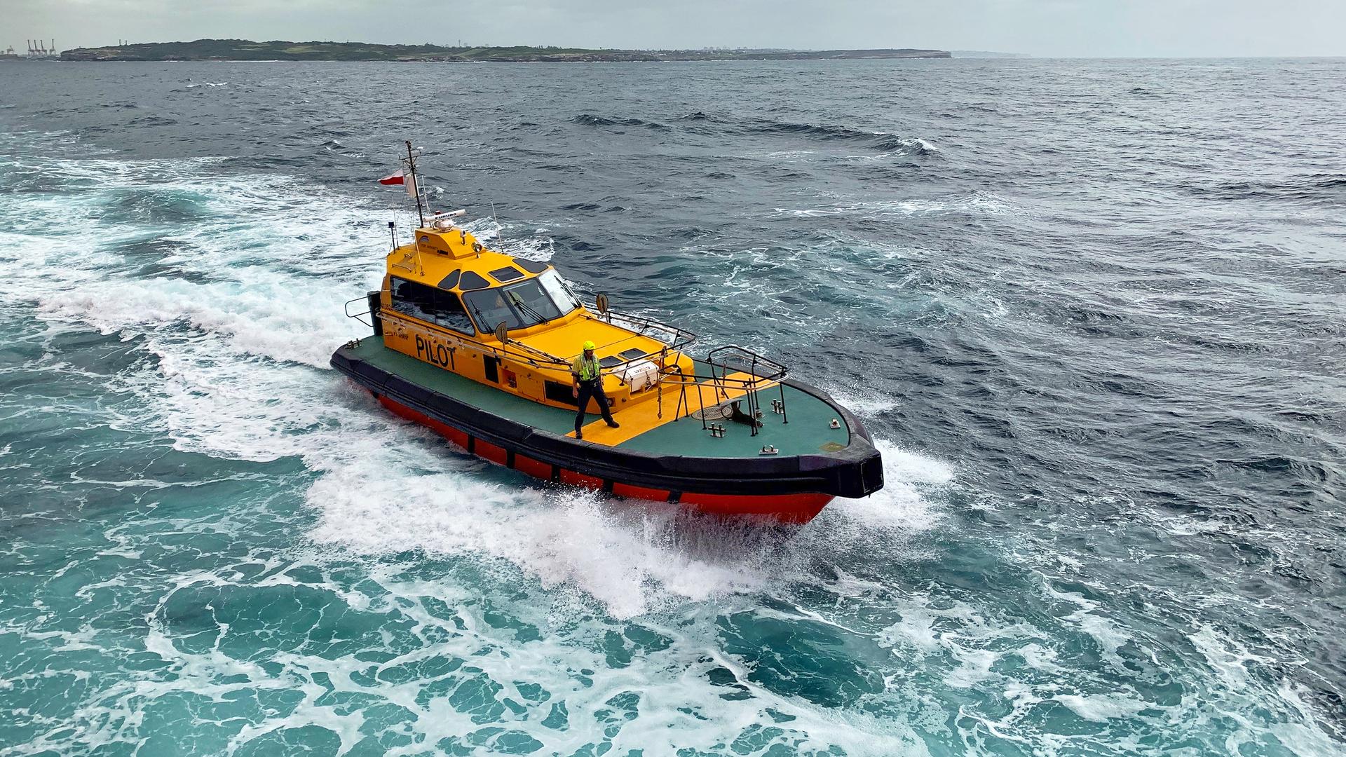 A pilot stands at the front of a pilot vessel at sea off Port Botany 