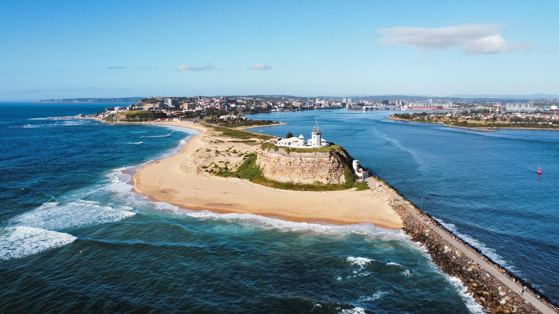 Aerial view of Nobbys Headland taken from over the water with Newcastle in the background