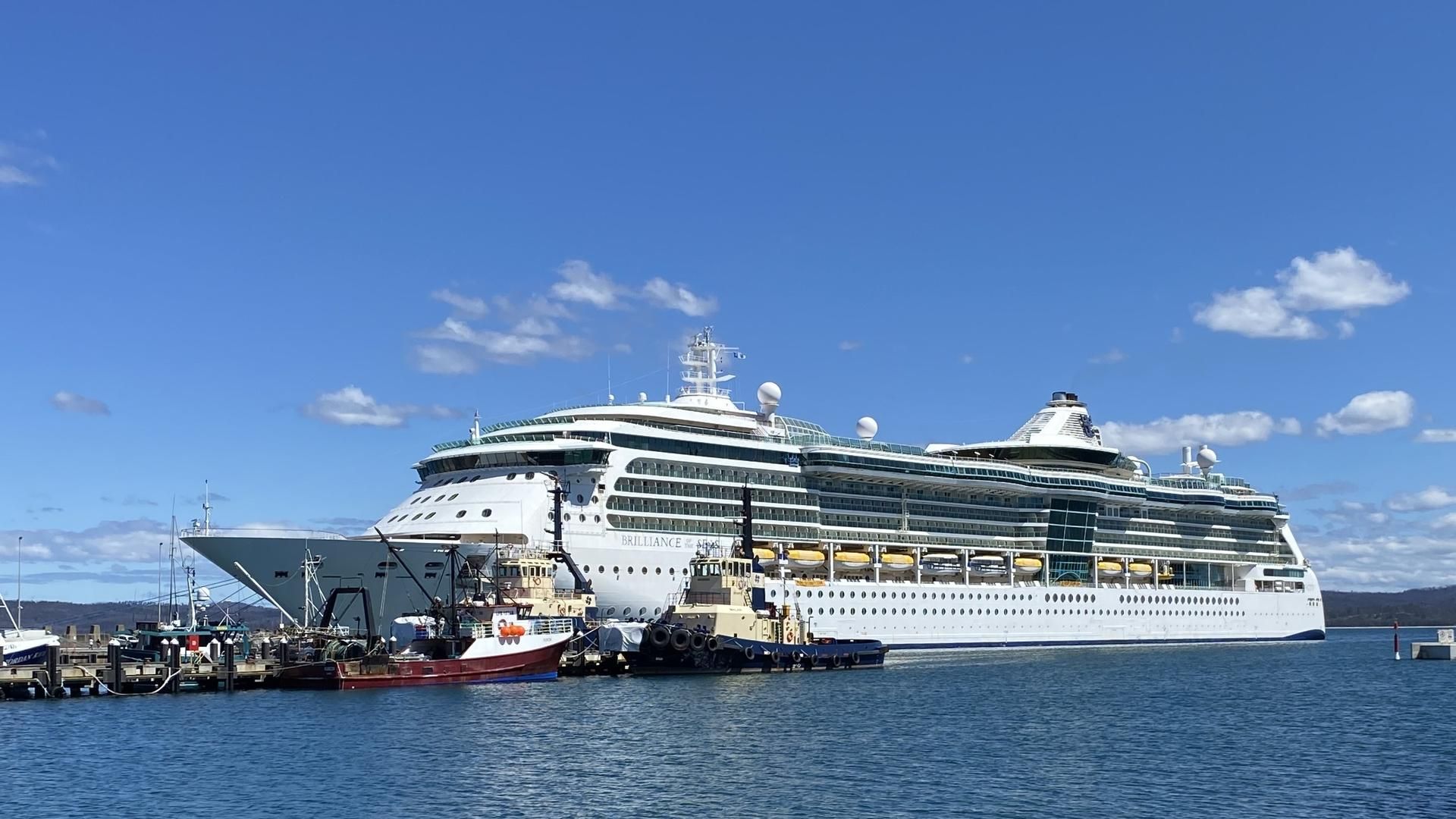 Large cruise ship moored at Eden with two tugs alongside on a sunny day