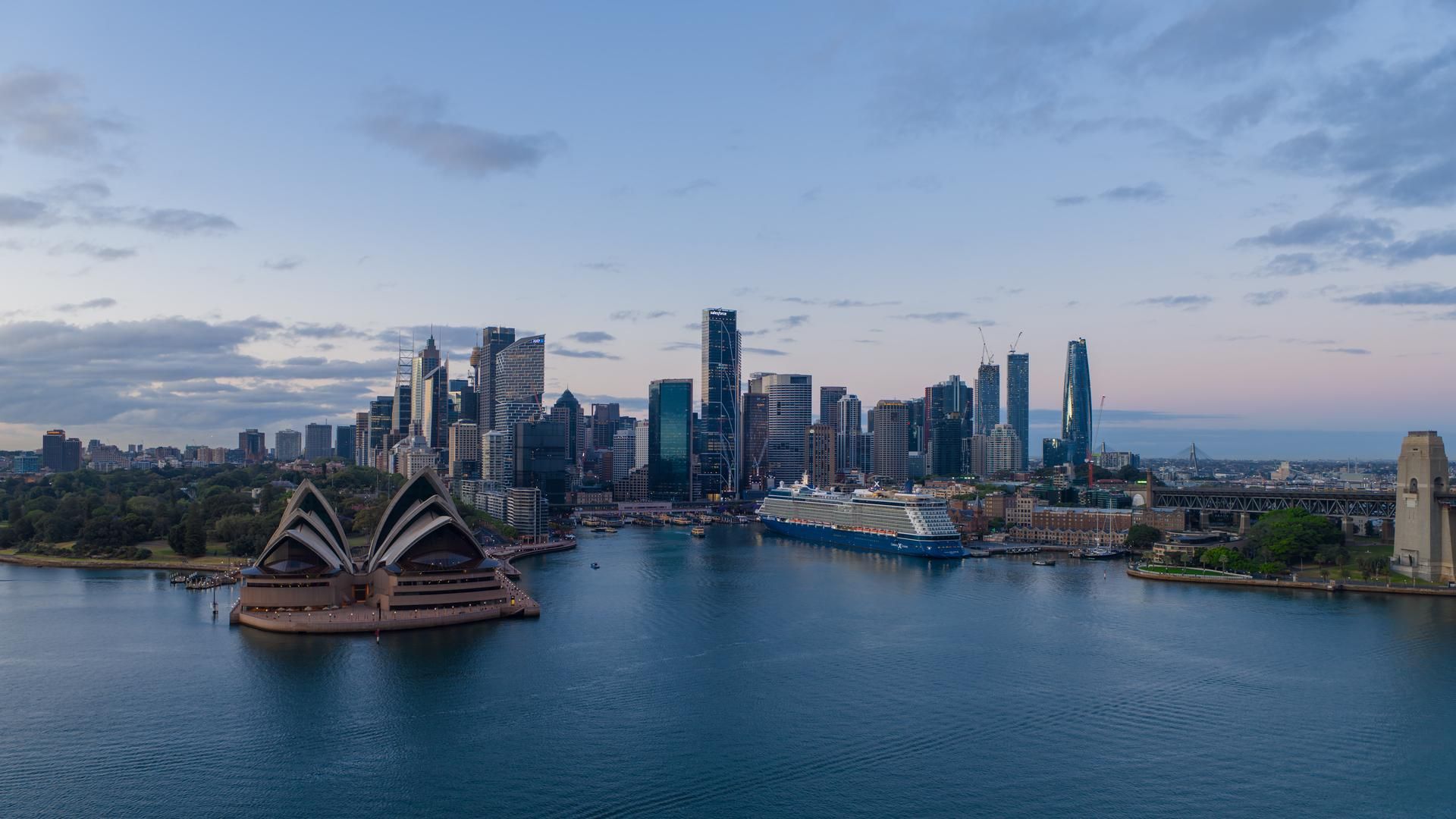 The CBD and Opera House at sunrise with a cruise ship moored at the Overseas Passenger Terminal and still waters