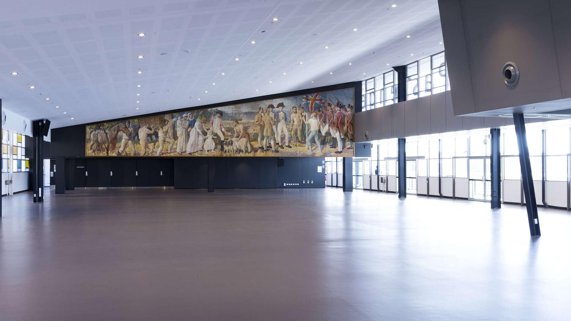 Inside the empty Customs Hall with an artwork of early settlers on the wall